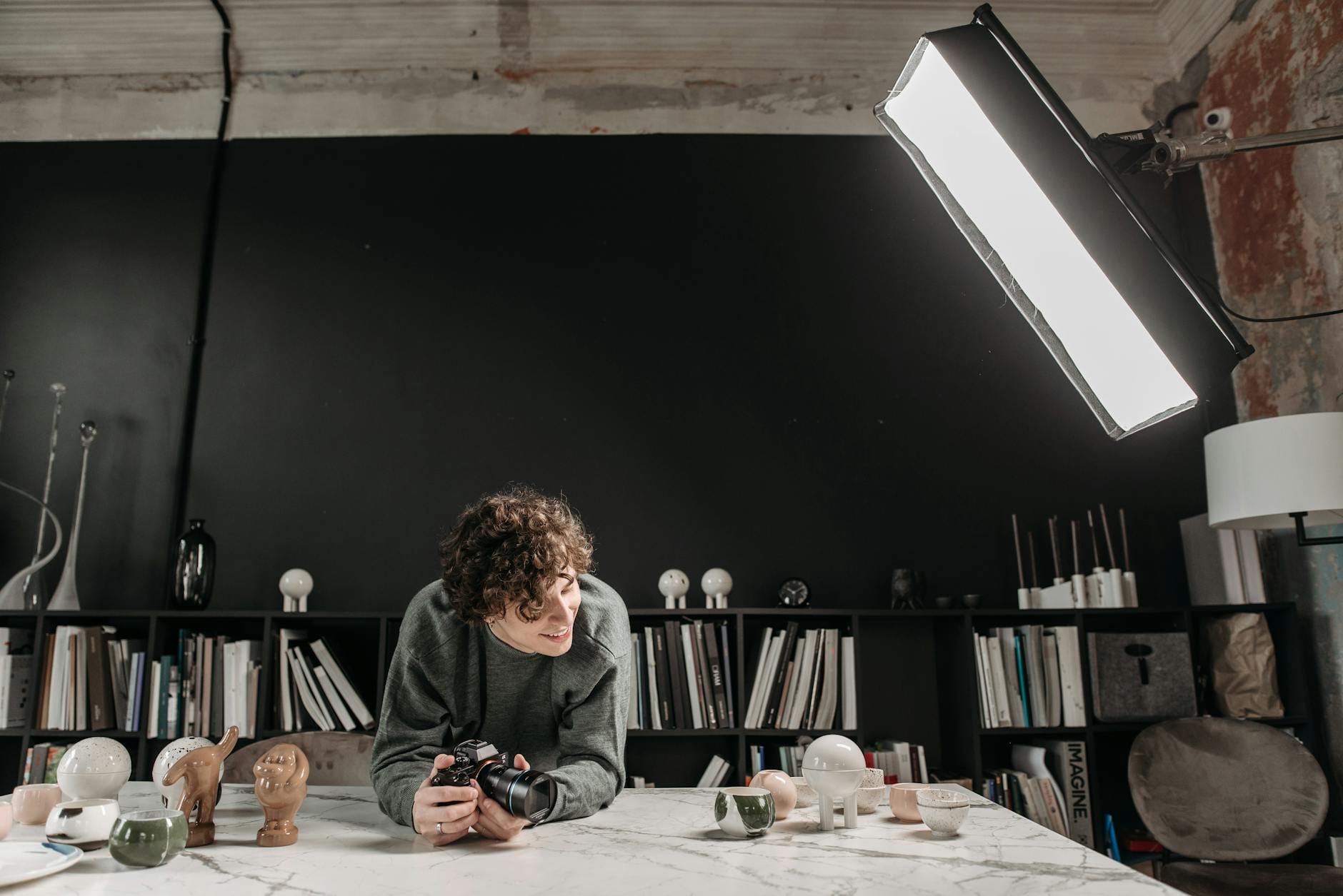 Fotograf w studiu z ceramiką i książkami testuje sprzęt oświetleniowy