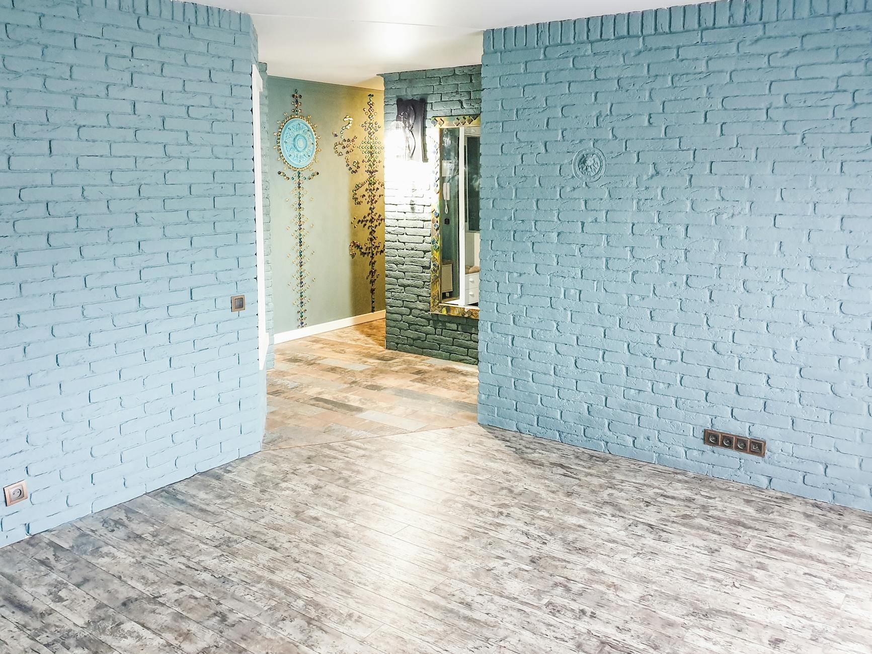 Jasne mieszkanie z niebieską ceglaną ścianą i drewnianą podłogą