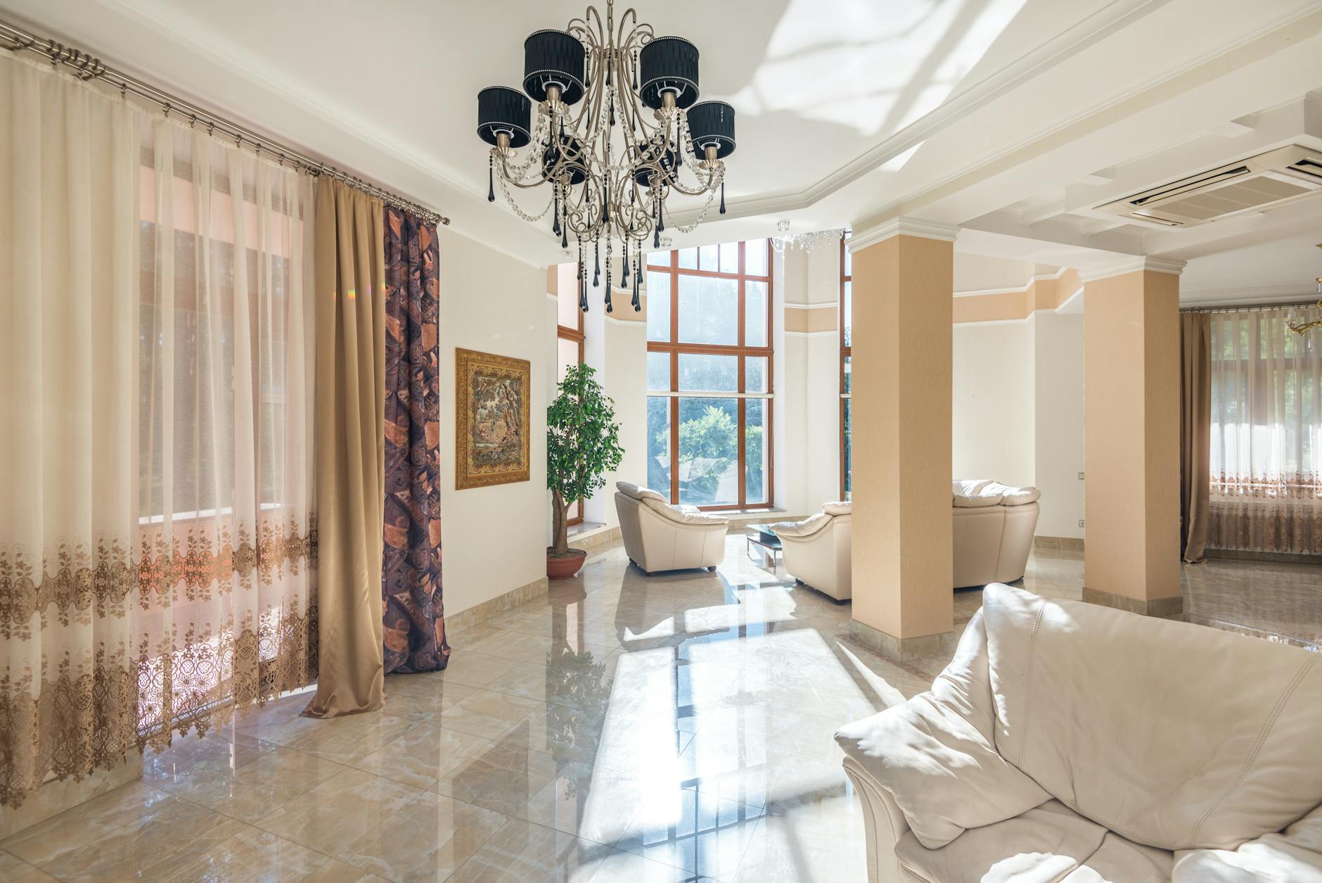 Przestronny salon z żyrandolem, dużymi oknami i miękką sofą