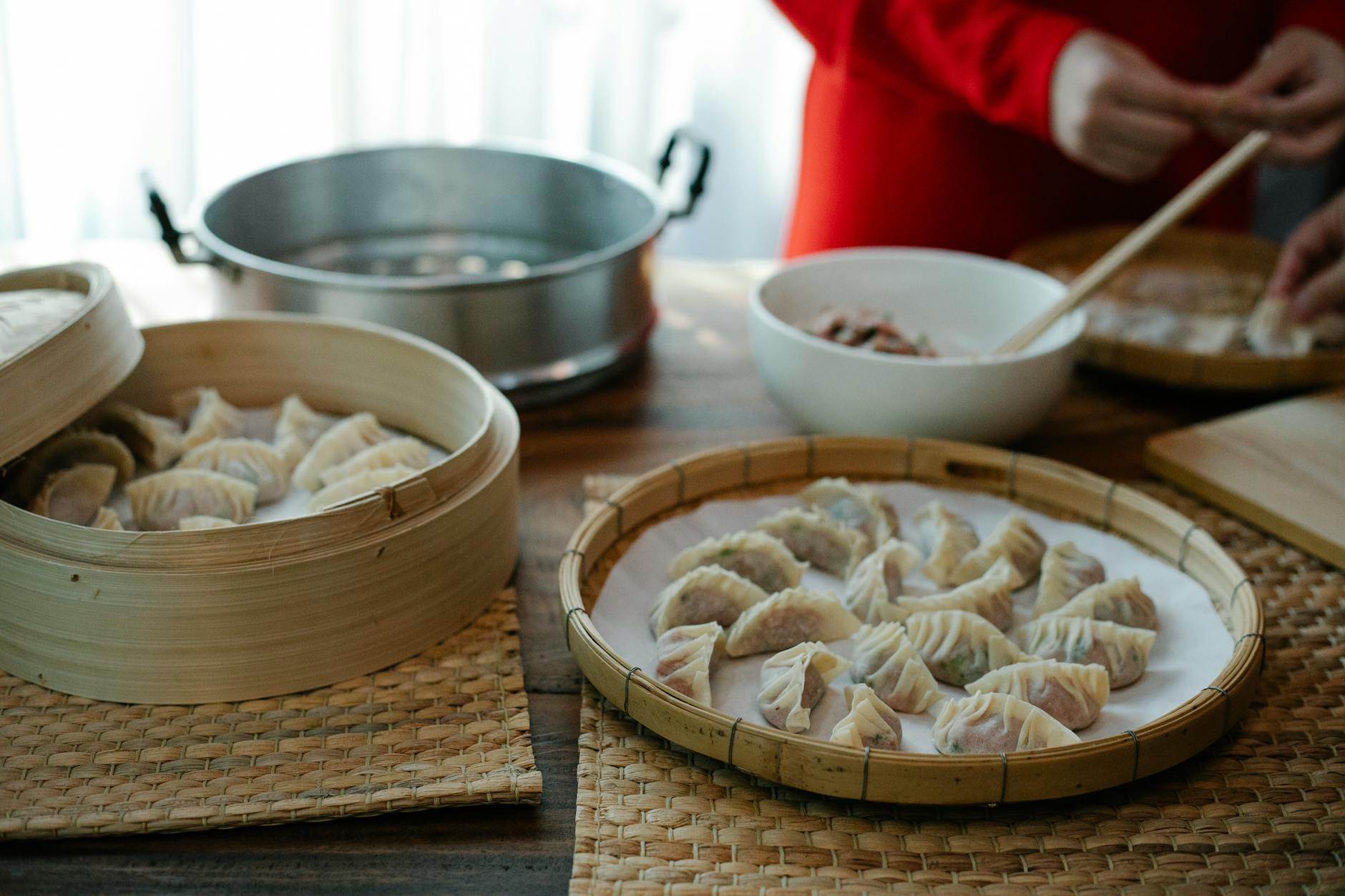 Kobiece ręce lepią chińskie pierożki jiaozi w domowej kuchni