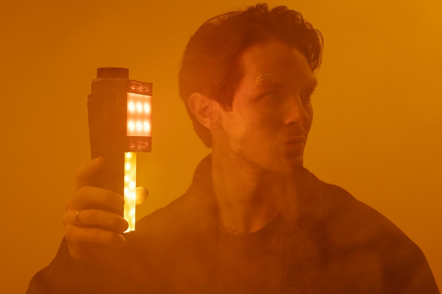 Mężczyzna w studio trzyma w dłoni lampę LED w przyciemnionym świetle