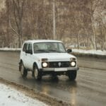 Białe terenowe auto jedzie zimową, ośnieżoną drogą