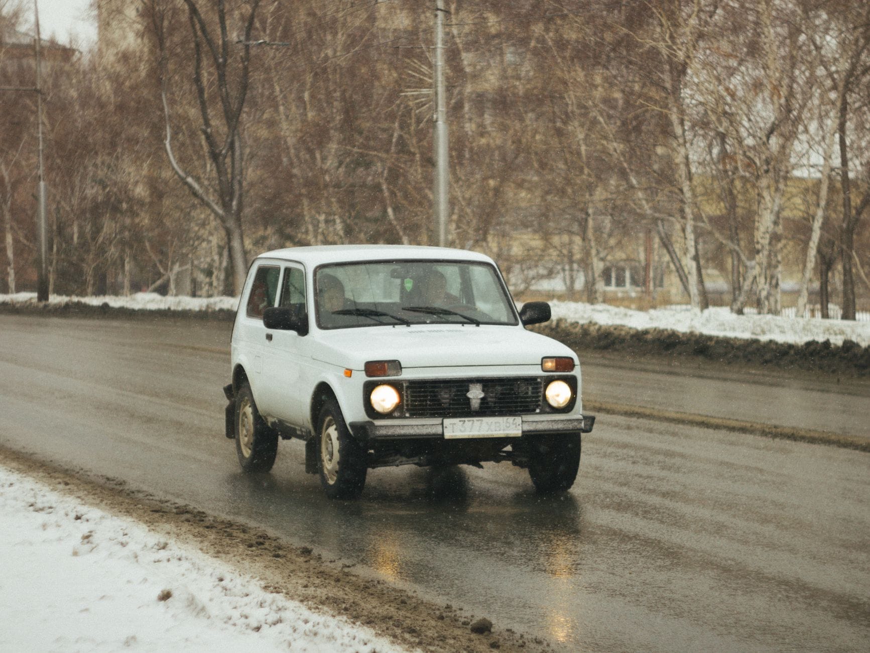 Białe terenowe auto jedzie zimową, ośnieżoną drogą