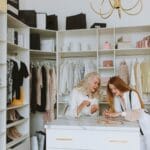 Dwie eleganckie kobiety przy luksusowej garderobie pełnej ubrań
